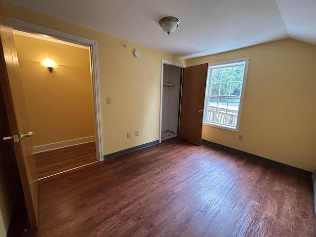 unfurnished bedroom featuring vaulted ceiling, wood finished floors, baseboards, and a closet