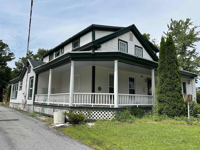 view of side of home with covered porch and a lawn