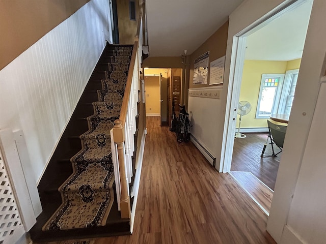 stairway with a baseboard radiator, baseboards, baseboard heating, and wood finished floors