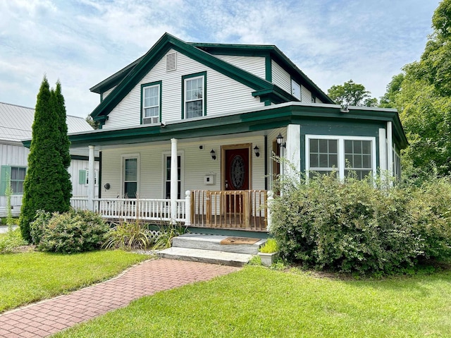 view of front of home with covered porch, metal roof, and a front yard