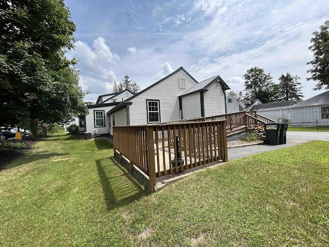 rear view of property with a wooden deck and a yard