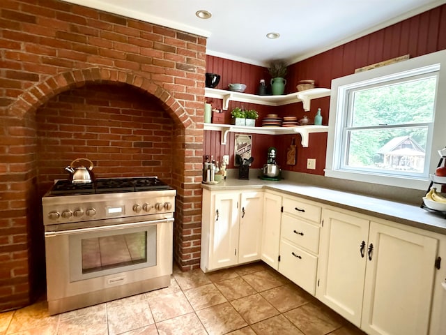 kitchen featuring light tile patterned flooring, double oven range, and brick wall