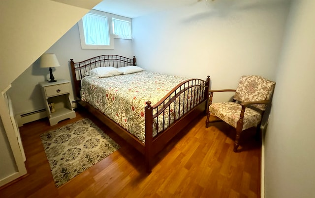 bedroom with hardwood / wood-style flooring and baseboard heating