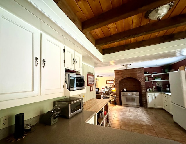 kitchen featuring white cabinetry, stainless steel appliances, brick wall, beamed ceiling, and wood ceiling