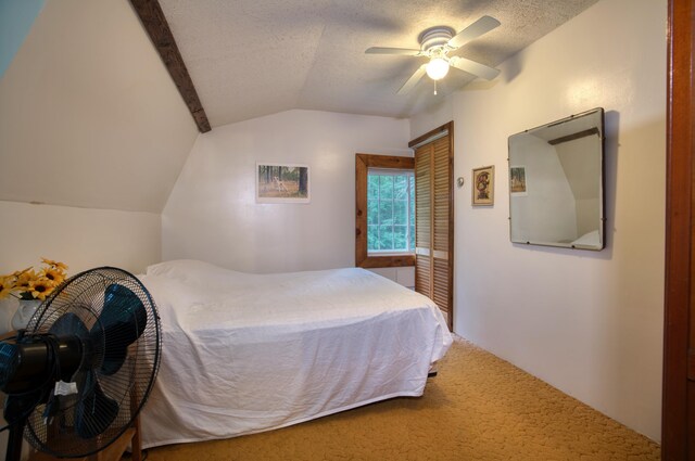 bedroom featuring a textured ceiling, ceiling fan, vaulted ceiling, a closet, and carpet floors