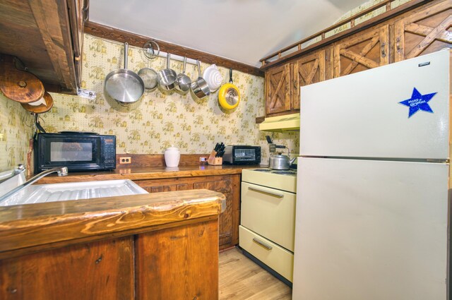 kitchen featuring white appliances, light wood-type flooring, custom range hood, and sink