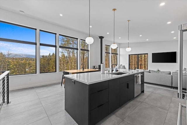 kitchen featuring modern cabinets, an island with sink, a sink, light countertops, and dark cabinets