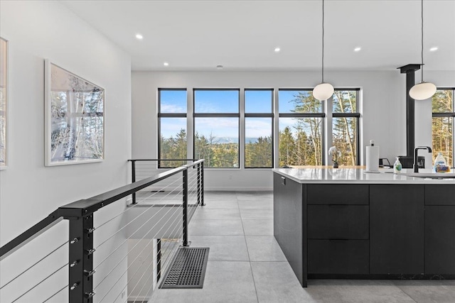 kitchen with a sink, modern cabinets, dark cabinetry, and pendant lighting