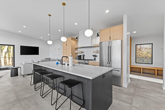 kitchen with light brown cabinetry, high end fridge, a healthy amount of sunlight, and a sink