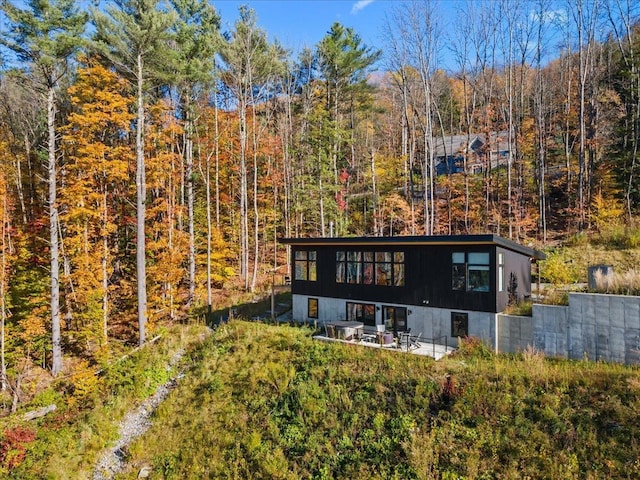 back of house featuring a view of trees