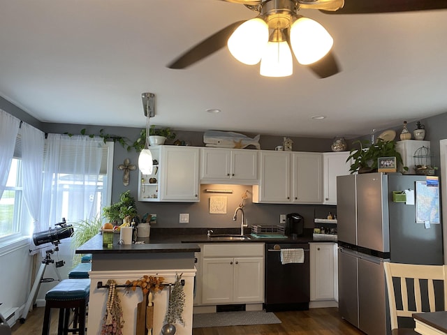 kitchen featuring dark countertops, dishwasher, freestanding refrigerator, white cabinets, and a sink