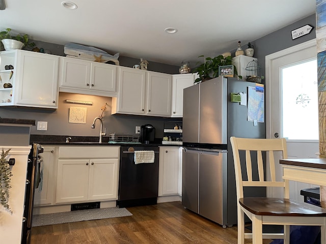 kitchen with black dishwasher, freestanding refrigerator, dark wood-style floors, white cabinetry, and a sink