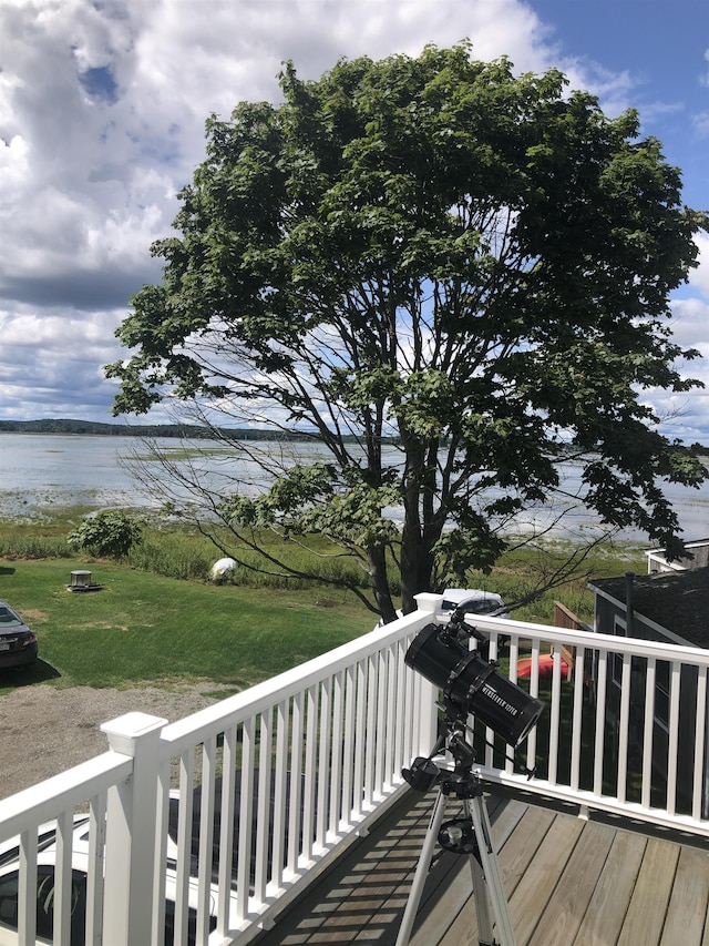 wooden terrace featuring a water view and a lawn