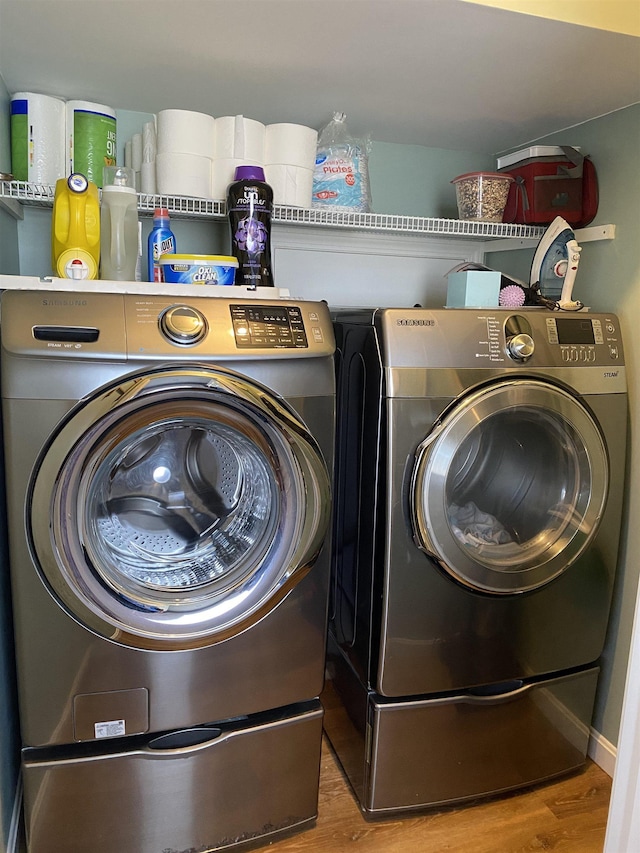 washroom featuring washer and dryer, wood finished floors, and laundry area