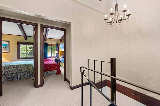 hall with beamed ceiling, an inviting chandelier, and carpet floors