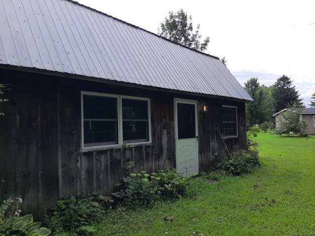 exterior space featuring metal roof, board and batten siding, and a yard