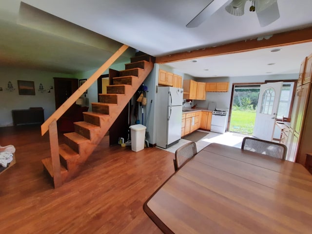 dining room with light wood-style flooring, beamed ceiling, stairway, and ceiling fan