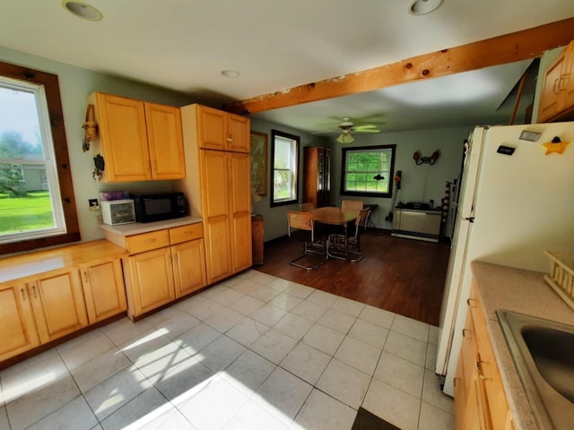 kitchen featuring black microwave, light tile patterned floors, a sink, light countertops, and freestanding refrigerator