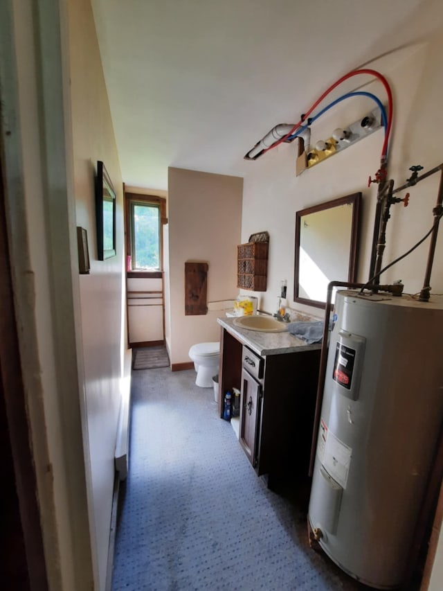 bathroom featuring baseboards, electric water heater, vanity, and toilet