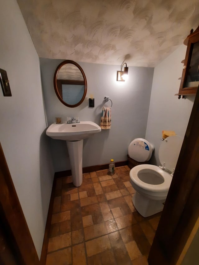 half bath featuring toilet and baseboards