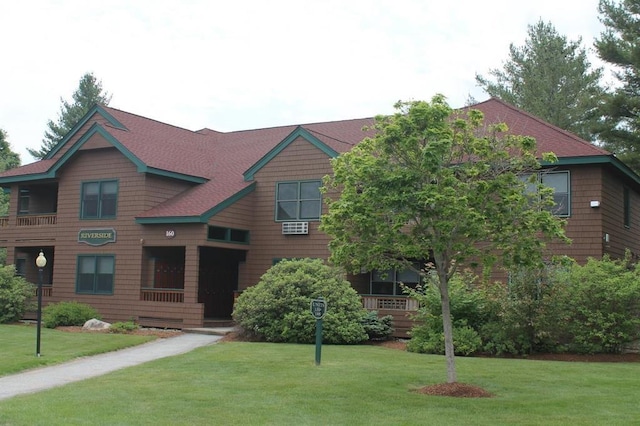 view of front of home with roof with shingles and a front yard