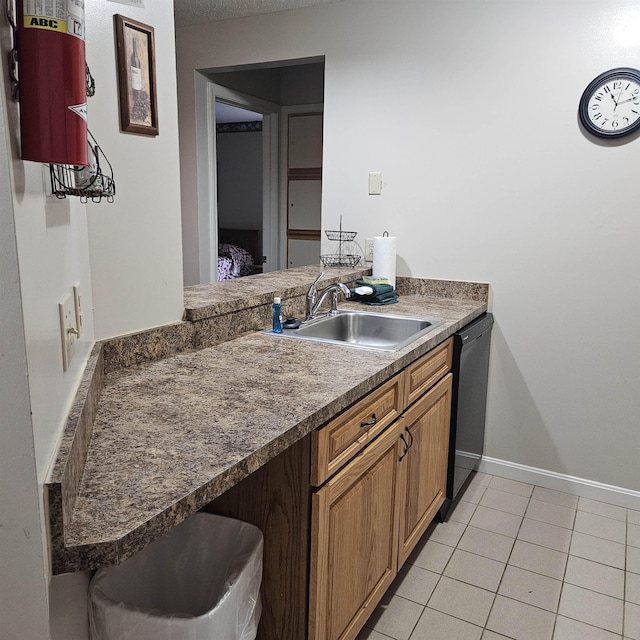 kitchen with brown cabinets, dishwasher, a sink, dark countertops, and light tile patterned flooring