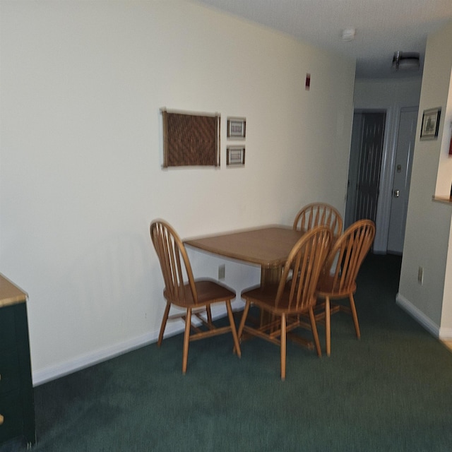 dining space featuring baseboards and dark carpet