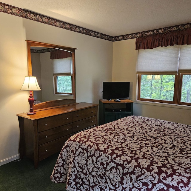 bedroom featuring dark colored carpet, baseboards, and a textured ceiling