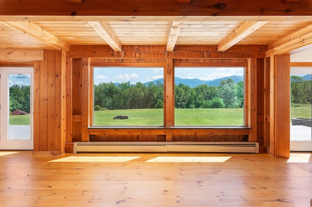 unfurnished sunroom featuring a healthy amount of sunlight, a mountain view, wooden ceiling, and beamed ceiling