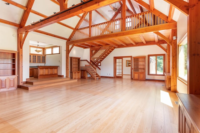 unfurnished living room with beam ceiling, high vaulted ceiling, and light hardwood / wood-style floors