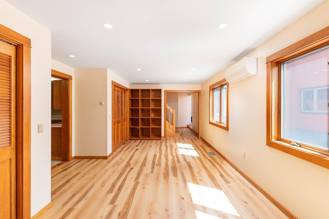 empty room featuring a wall unit AC and light hardwood / wood-style flooring