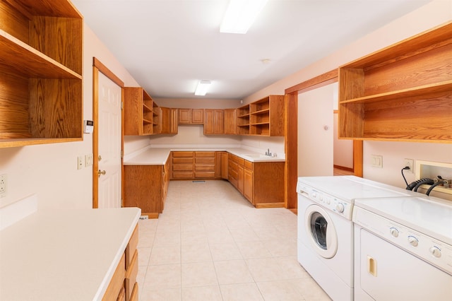 laundry room featuring separate washer and dryer, sink, light tile patterned floors, and cabinets