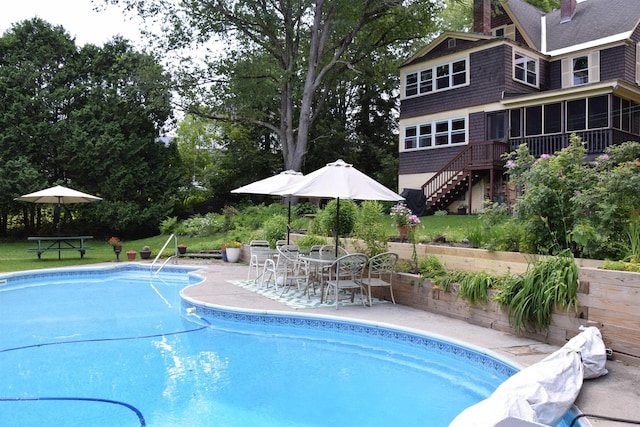 view of swimming pool featuring a patio and a sunroom