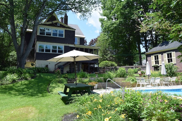 back of property with a fenced in pool and a lawn