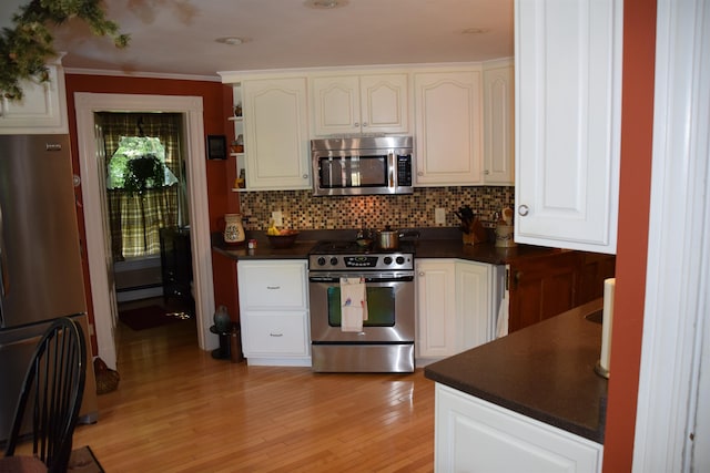 kitchen featuring white cabinetry, a baseboard radiator, backsplash, stainless steel appliances, and light hardwood / wood-style flooring