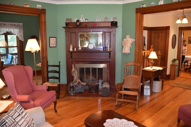 sitting room featuring hardwood / wood-style flooring, ornamental molding, and an inviting chandelier