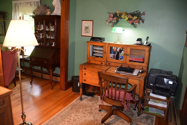 home office with a baseboard heating unit and light hardwood / wood-style flooring