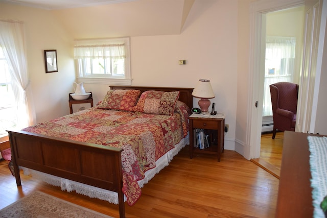 bedroom with light hardwood / wood-style floors and a baseboard heating unit