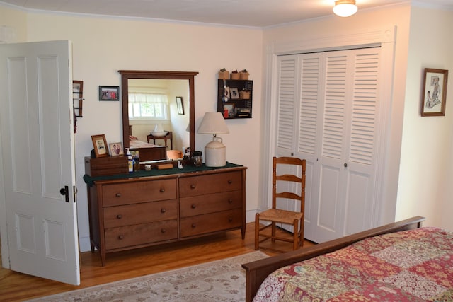 bedroom featuring crown molding, light wood-type flooring, and a closet