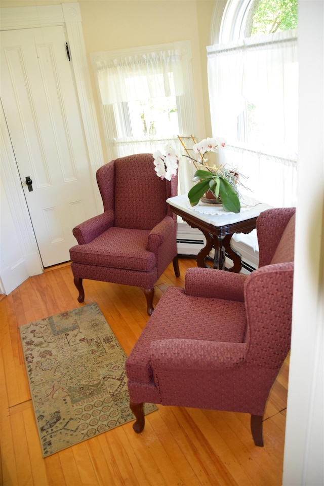 living area with hardwood / wood-style flooring and a baseboard heating unit