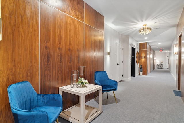 sitting room featuring wood walls and light colored carpet