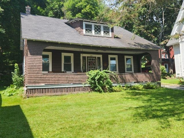 view of front of property featuring covered porch and a front lawn