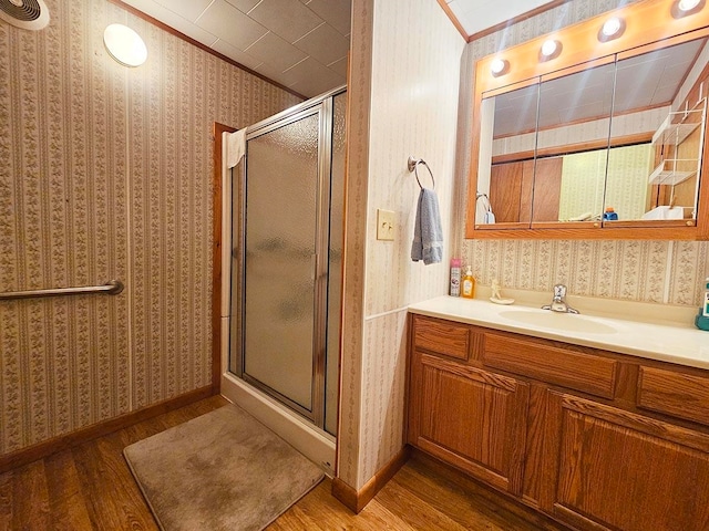 bathroom featuring vanity, hardwood / wood-style flooring, crown molding, and a shower with door