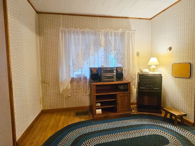 sitting room with ornamental molding and wood-type flooring