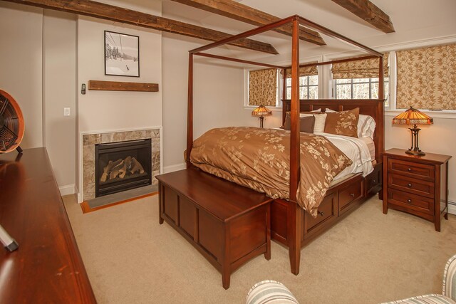 bedroom with a fireplace, light carpet, and beam ceiling