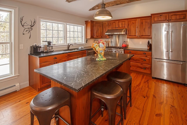 kitchen featuring a center island, appliances with stainless steel finishes, sink, light hardwood / wood-style floors, and decorative light fixtures