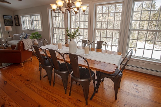 dining room featuring light wood-type flooring, a baseboard heating unit, and a chandelier