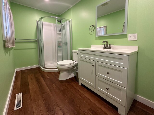 bathroom featuring hardwood / wood-style floors, a shower with shower door, vanity, and toilet