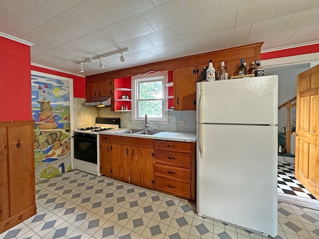 kitchen with backsplash, white appliances, track lighting, and sink