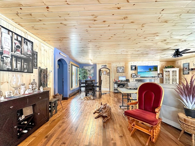 living area with arched walkways, wood ceiling, wood walls, and light wood-style flooring